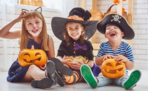 Three children holding pumpkins and candy